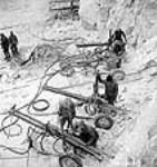 Des foreurs conduisent leurs porte-foreuses dans le chantier de terrassement du canal de fuite lors du projet d'aménagement hydroélectrique de Shipshaw janv. 1943