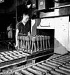 Workman placing Piat anti-tank gun bodies into an oven in a factory juin 1944