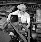 Une travailleuse façonne une pièce d'arme à l'usine de munitions de la John Inglis Co 10 Apr. 1944