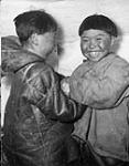Two boys playing in an igloo, Igloolik, Nunavut [The boy smiling at the camera is Dominic Angutimarik. He is the son of Isadore Tulugarjuk and Theresa Nattikuttuk (Nattiq) Tulugarjuk]  1953.