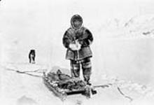 Inuit man out sealing with his komatik. Dog in background 1939.