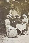 Four nurses gathered around a table under the shade of a palm tree, possibly in Greece vers 1916