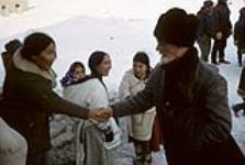 Group of Inuit [Lazuruie Pauktuut, Madeline Tulugaarjuk, Leonie Tulugaarjuk, and Melanie Inuksuk] with priest: one young Inuit is shaking the priest's hand [graphic material] May 1965.