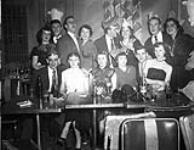 Customers at the Standish Hall Hotel posing at their table, some wearing paper hats. It is possibly New Year's Eve ca 1941-1952.