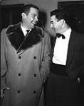 Singer Dick Haymes (L) in fur trimmed coat laughing with man after performance at the Standish Hotel. Dick Haymes was a popular Argentinian-born American singer ca 1950.