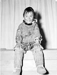 [Inuit boy sitting on a bench in front of a curtain, taken at Iqaluit (formerly Frobisher Bay), Nunavut] [1944].