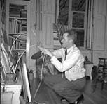 [Louis Muhlstock kneeling in front of paintings] 1941 ?.