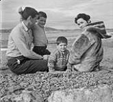[The Houston family sitting in a field, Cape Dorset, Nunavut] [between August 24-October 3, 1960].