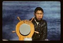 Sarpinak steering a boat, Iqaluit, Nunavut [between August 16-19, 1960]
