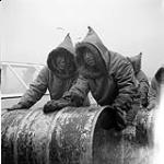 [Two men rolling an oil barrel] [between 1956-1960]