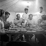 [Group of people socializing around a table inside of a tent] [between 1956-1960]
