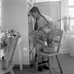 [Woman and Sam Houston baking in kitchen, Kinngait, Nunavut] [between 1956-1960]