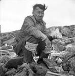 [Tudlik holding a small carving, Kinngait, Nunavut] [between 1956-1960]