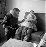 [Sam Houston (left) with a young child hugging Farleigh Allatt (right), Kinngait, Nunavut] [between 1956-1960]