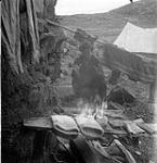 [Barbara Hinds drying clothes next to a fire on "Spyglassie Island," near Iqaluit, Nunavut] 1960