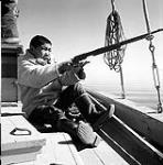 [Sarpinak aiming a rifle, Iqaluit, Nunavut] 1960