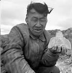 [Tudlik holding up a carving of an owl, Kinngait, Nunavut] 1960