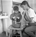 [Sam Houston and a girl mixing ingredients, Kinngait, Nunavut] 1960