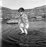 [Sam Houston playing in the water, Kinngait, Nunavut] 1960