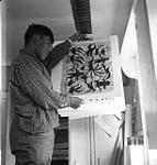 [Artist Eegyvudluk Pootoogook hanging a print to dry, Kinngait, Nunavut] 1960
