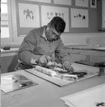 [Iyola Kingwatsiak making prints, Kinngait, Nunavut] 1960
