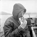 [Mackenzie Porter eating bannock while on a boat, Kinngait, Nunavut] 1960
