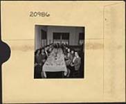 People gathered at a table to dine mars 1946