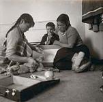 [Sam Houston and two Inuit girls playing with toys] [between 1956-1960]