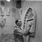 William Oosterhoff With Sculpture and Masks in the Background [ca 1954-1963].