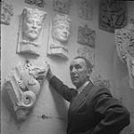 William Oosterhoff poses with stone sculptures [ca1954-1963]