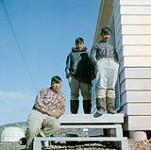 Trois graveurs dehors près du centre d'artisanat de Cape Dorset, Cape Dorset, T.N.-O., [Cape Dorset (Kingnait), Nunavut] [between June-September, 1960].
