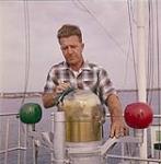 Mate Ches Bishop cleaning the binnacle on the compass on the deck of the M.V. Christmas Seal. Newfoundland August 1960