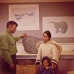An eskimo family in print room at Cape Dorset, Baffin Island. Lucy, the woman is one of the graphic artists at Cape Dorset.  [Inuk artist Lucy Pootoogook and Inuk Eegyvudluk Pootoogook with Lucy's child, Iyola Kingwats] juillet 1961