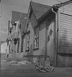 Toronto, deux garçons assis sur la bordure d'un trottoir à l'extérieur d'un logement [between 1939-1951].