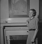 Winnipeg, années 1940. Plan rapproché d'une femme non identifiée accoudée au manteau de la cheminée [between 1940-1949]