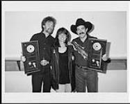Portrait of the duo Brooks and Dunn holding an award for their album Borderline. Also pictured is BMG Marketing Manager Jill Snell [ca 1996]