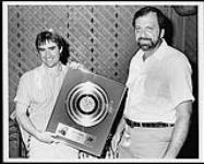 Le vice-président directeur et directeur général d'A&M, Joe Summers, remet un disque d'or à Chris De Burgh pour le disque longue durée « Man on the line » [ca. 1993].