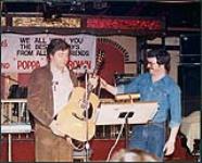 Poppa Brown debout sur scène et tenant une guitare [between 1967-1975].