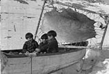 Three young Inuit boys in a small boat 1951