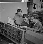 Captain Jim Mitchell (left) checks on the local Canadian newspaper 1958