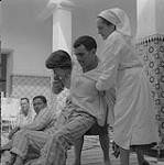 Margot Joncas helping a man with paralysis walk 1960