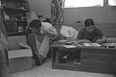 [Kenojuak Ashevak drawing at home as husband Joanassie Igiu looks on] December 1980