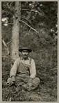 [Anishinaabe man, identified as Neodjigizik, seated outside] 1920