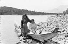 Two Gitxsan First Nation girls in a dugout cedar canoe by the Skeena River at Kitwanga (Gitwangak/Gitwangax), British Columbia  1915.