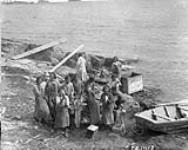 Aboriginal girls from the Roman Catholic Mission cleaning fish by the shore, Fort Chipewyan, Alberta, 1927 1927
