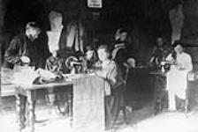 A communal sewing room. Clothing was standardized and issued periodically to every member of the community. n.d.