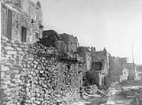 Hopi architecture [Arizona], the housewalls are about 18 inches thick and consist of fragments of sandstone, shaped by fracture but undressed and bound together with mud plaster.  The upper levels of the terraced buildings are reached by ladders.. 1922