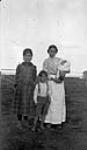 First Nations children and a woman holding a baby in a moss bag, Ile-à-la-Crosse, Saskatchewan  n.d.