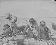 Four Inuit men sitting by the shore, Baker Lake (Qamanittuaq), Northwest Territories [Nunavut] 1893