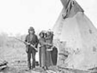 [Saulteux couple, James Quesace on left, with their child in a cradleboard, vicinity of the Upper Assiniboine River, Manitoba] Saulteux Indians from Upper Assiniboine River 16 Ot. 1887